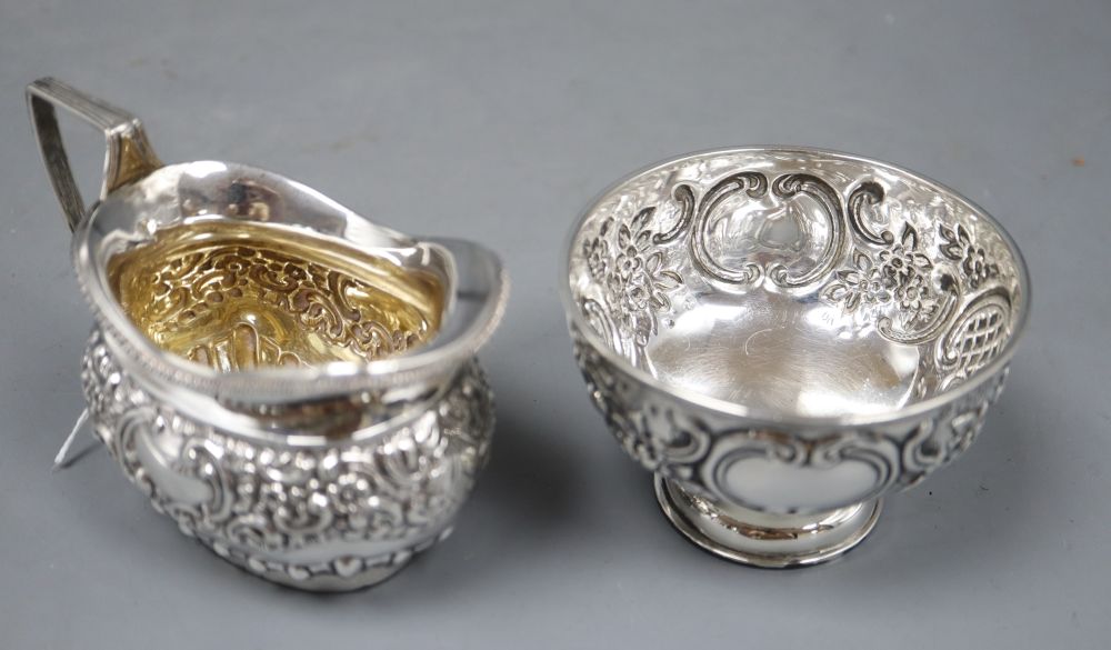A late Victorian embossed silver sugar bowl, London, 1899 and a later similar cream jug, 6oz.